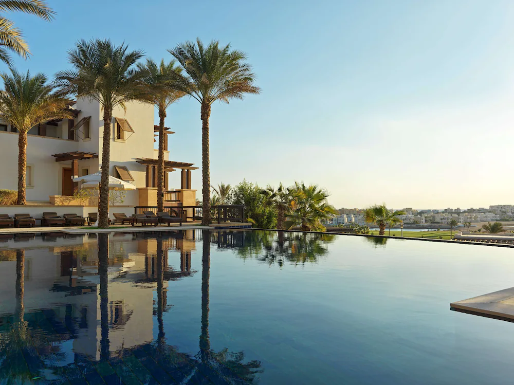 Pool beside a palm-lined holiday property under a clear sky